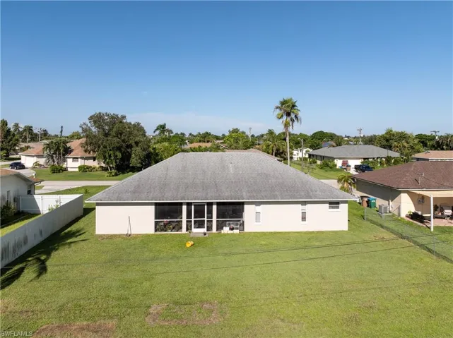 Back of property with a backyard, a residential view, a patio, and roof with shingles