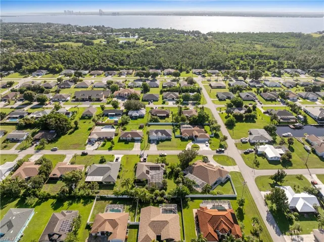 Aerial perspective of suburban area featuring a nearby body of water and a tree filled landscape