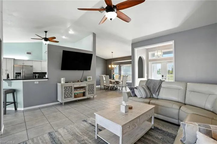 Living room with a ceiling fan, light tile patterned floors, a chandelier, and high vaulted ceiling