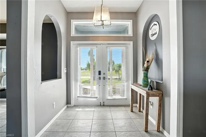 Doorway to outside featuring french doors, tile patterned floors, and arched walkways