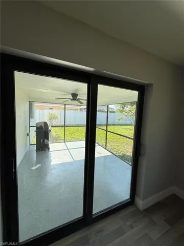 Doorway featuring a ceiling fan, wood finished floors, and baseboards