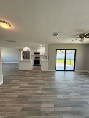 Unfurnished living room featuring baseboards, a sink, and a textured ceiling