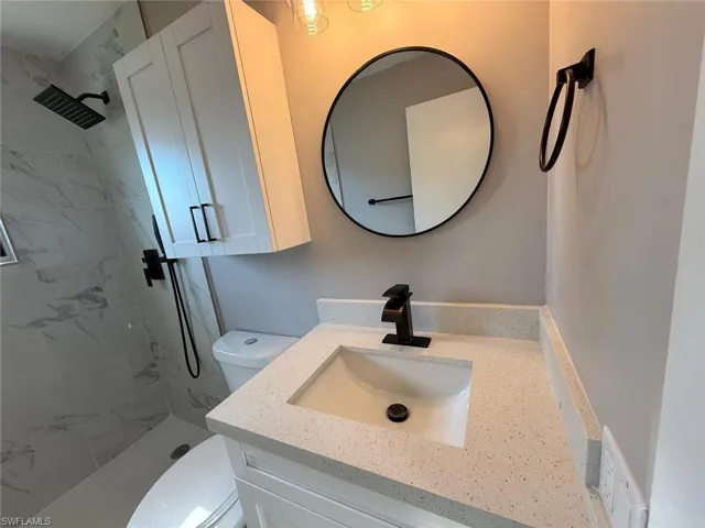 Bathroom featuring a stall shower, vanity, and toilet