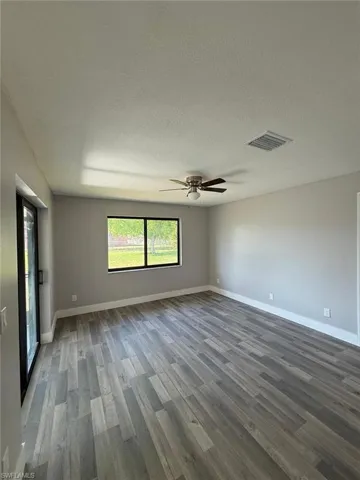 Spare room with a textured ceiling, baseboards, ceiling fan, visible vents, and wood finished floors