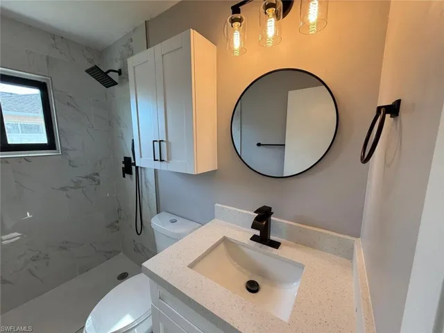 Full bath with vanity, toilet, and tiled shower
