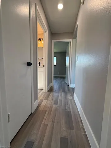 Corridor featuring baseboards and dark wood finished floors