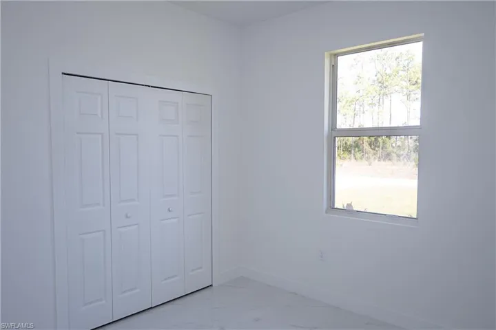 Unfurnished bedroom with baseboards, a closet, and marble finish floor