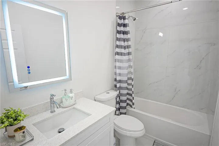 Bathroom with shower / bath combo with shower curtain, toilet, and vanity
