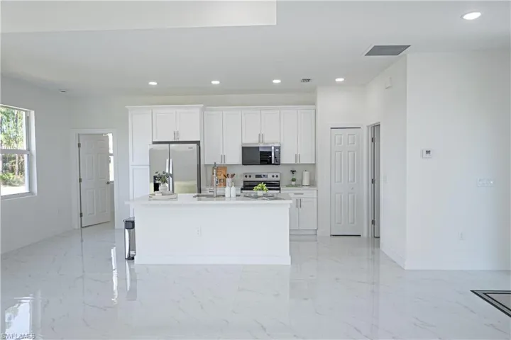 Kitchen with visible vents, an island with sink, recessed lighting, white cabinetry, and stainless steel appliances