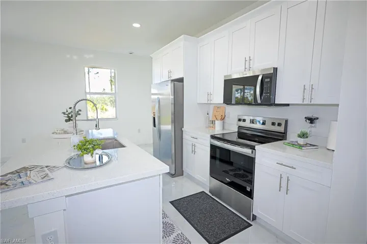 Kitchen with white cabinetry, appliances with stainless steel finishes, a sink, and recessed lighting