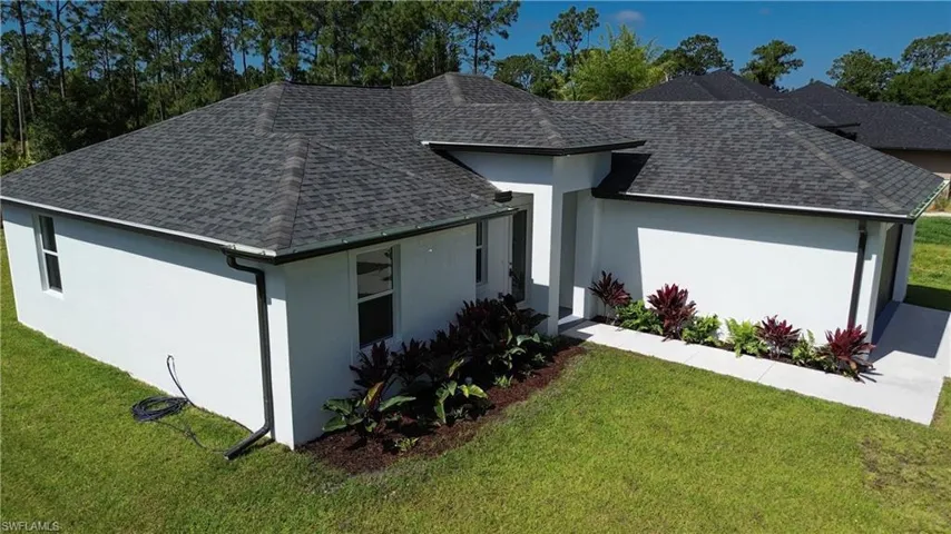 Ranch-style home with roof with shingles, stucco siding, and a front yard