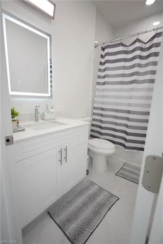 Bathroom with toilet, marble finish floor, and vanity