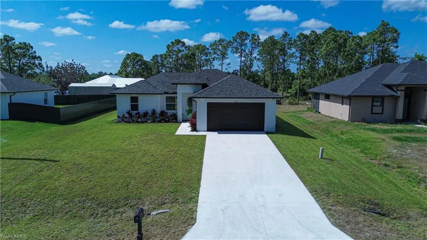 Ranch-style home with a front yard, a garage, fence, concrete driveway, and stucco siding