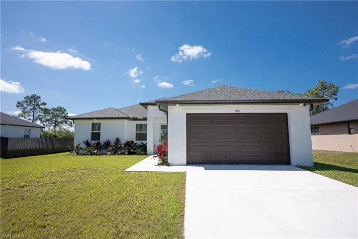 View of front of house with fence, a front lawn, concrete driveway, an attached garage, and stucco siding