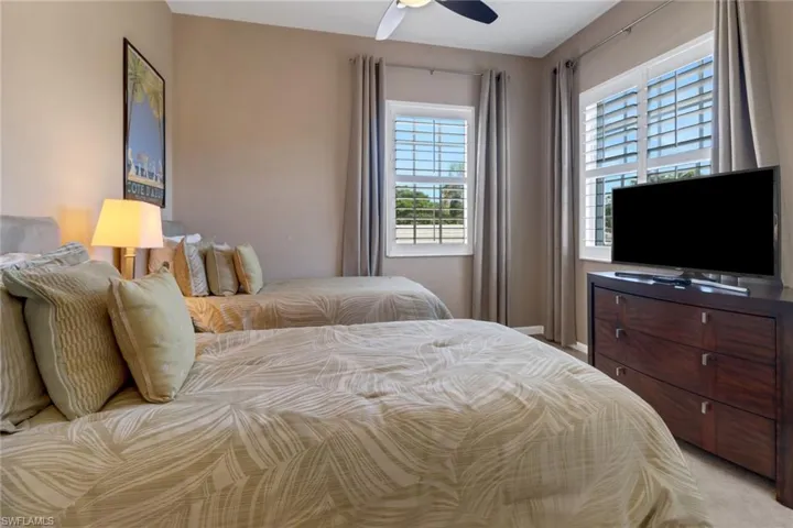 Bedroom with ceiling fan, light carpet, and multiple windows