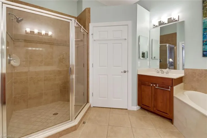 Bathroom featuring tile patterned floors, vanity, and separate shower and tub