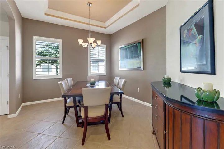 Dining space featuring an inviting chandelier, a tray ceiling, and light tile patterned floors