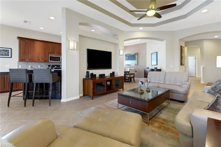 Living room with ornamental molding, ceiling fan, a raised ceiling, and light tile patterned floors