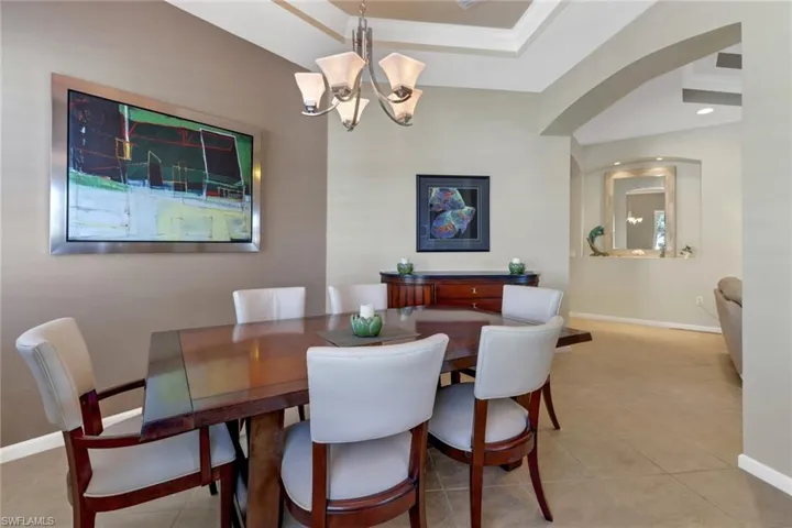 Tiled dining space featuring ornamental molding and a chandelier