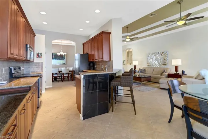 Kitchen featuring appliances with stainless steel finishes, ceiling fan with notable chandelier, tasteful backsplash, and a breakfast bar