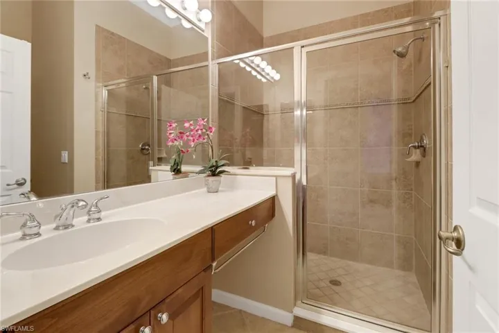 Bathroom with vanity, a shower with shower door, and tile patterned flooring