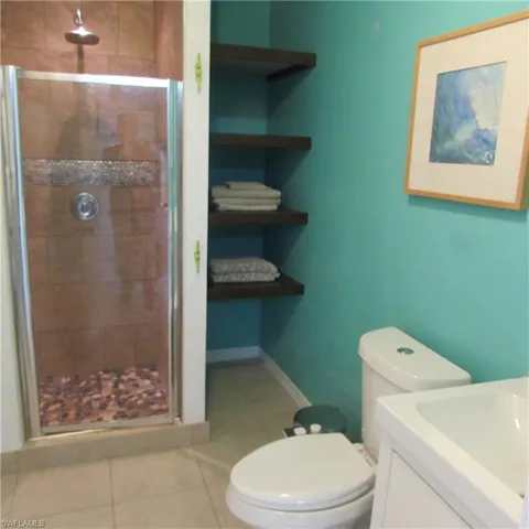 Bathroom featuring tile patterned flooring, vanity, toilet, and an enclosed shower