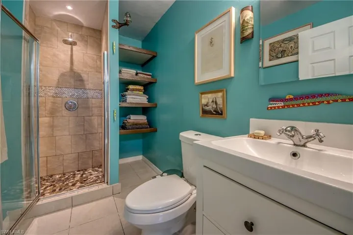 Bathroom featuring tile patterned floors, vanity, an enclosed shower, and toilet