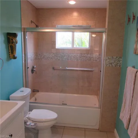 Full bathroom featuring tile patterned floors, vanity, enclosed tub / shower combo, and toilet