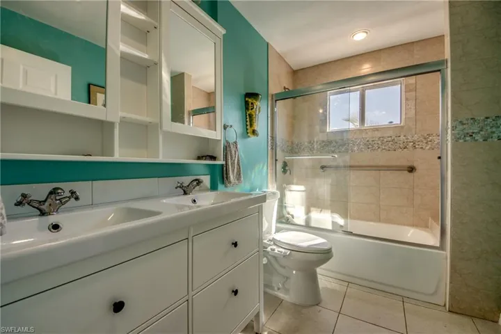 Full bathroom featuring tile patterned floors, vanity, toilet, and bath / shower combo with glass door