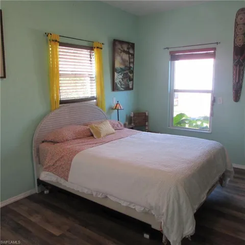 Bedroom featuring multiple windows and dark hardwood / wood-style flooring