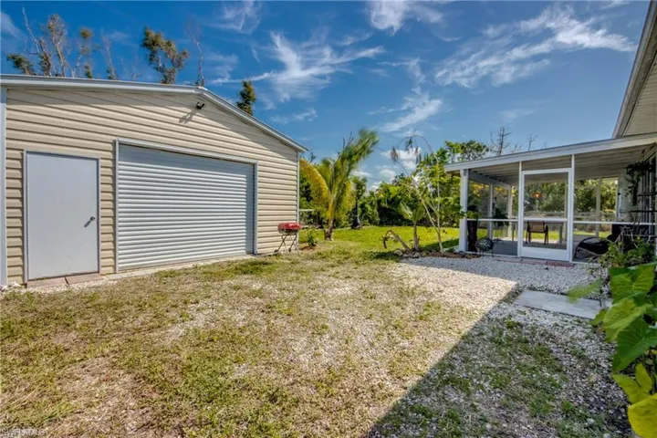 View of yard featuring a sunroom, a garage, and an outdoor structure
