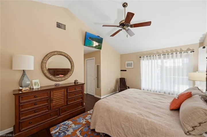 Vaulted ceiling with a ceiling fan, recessed door, and wood-finish flooring