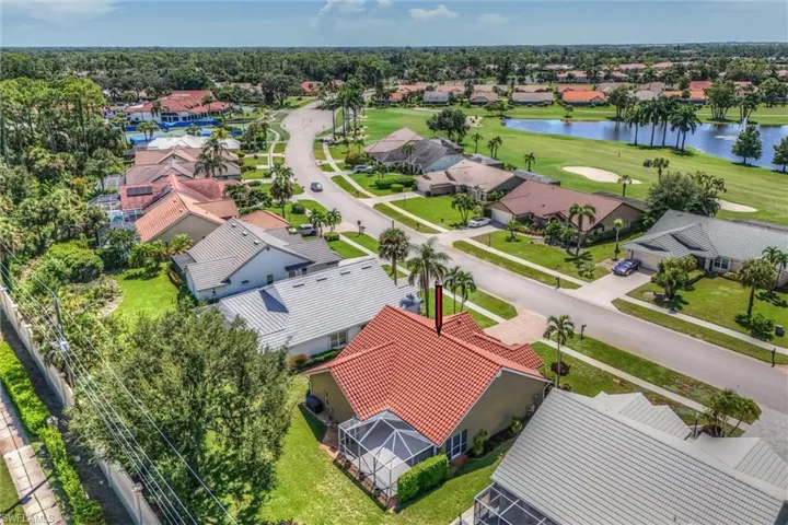 Residential neighborhood with lush landscaping, paved roads, and a golf course with water features