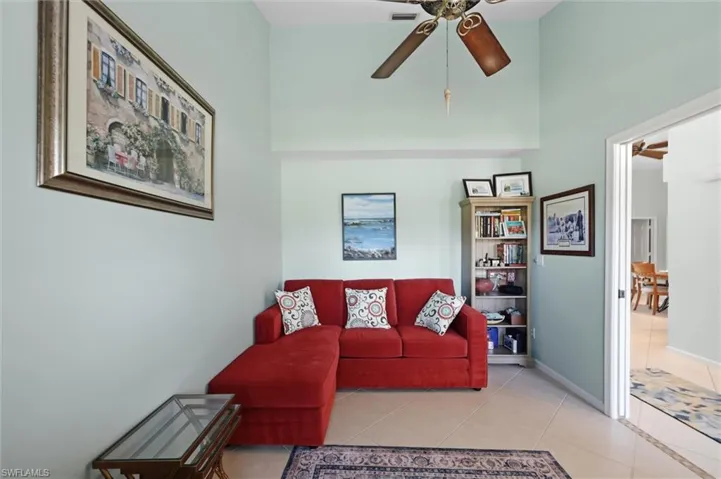 Vaulted ceiling with an installed ceiling fan, tile flooring, and a built-in bookshelf