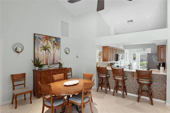 Vaulted ceiling, open kitchen pass-through, recessed lighting, tile flooring, and built-in cabinetry