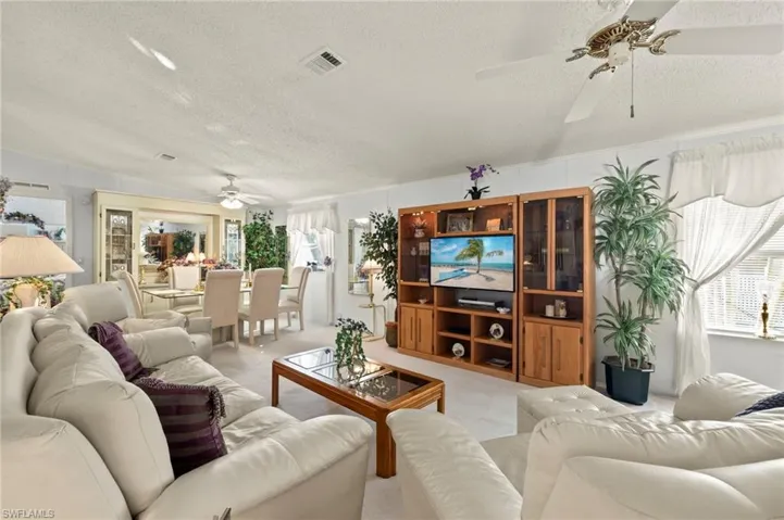 Carpeted living room with ceiling fan and a textured ceiling.  Furniture stays with home.