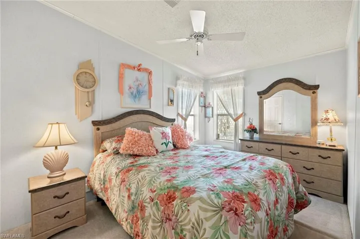 Bedroom featuring ceiling fan, crown molding, carpet floors, and a textured ceiling.  FURNITURE STAYS