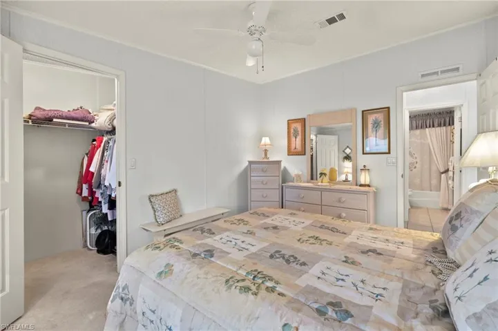 Carpeted bedroom with a walk in closet, a textured ceiling, ceiling fan, connected bathroom, and a closet