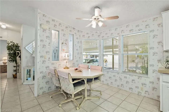 Dining area with crown molding, light tile patterned flooring, a textured ceiling, and ceiling fan