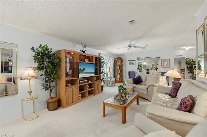 Carpeted living room with a textured ceiling and ceiling fan