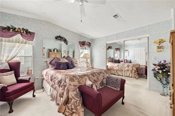 Bedroom with ceiling fan, a textured ceiling, lofted ceiling, light carpet, and a walk in closet.  FURNITURE STAYS