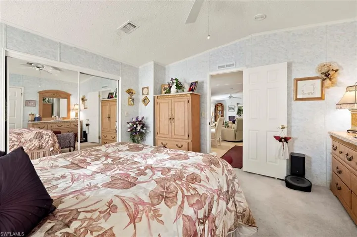 Carpeted bedroom with ceiling fan, crown molding, a textured ceiling, and vaulted ceiling