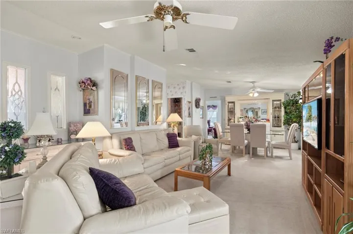 Carpeted living room featuring ceiling fan and a textured ceiling
