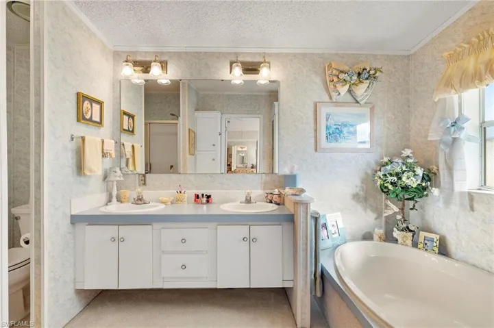 Full bathroom featuring a textured ceiling, toilet, vanity, independent shower and bath, and ornamental molding