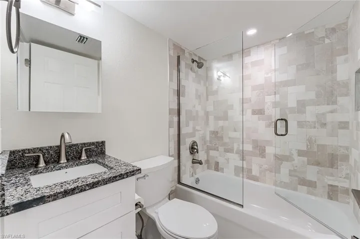 Bathroom featuring vanity, enclosed tub / shower combo, and recessed lighting