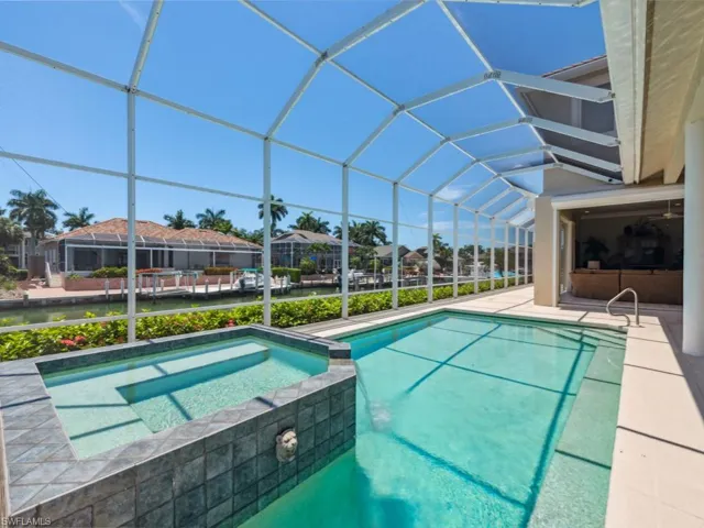 View of pool with a pool with connected hot tub, a patio area, and glass enclosure