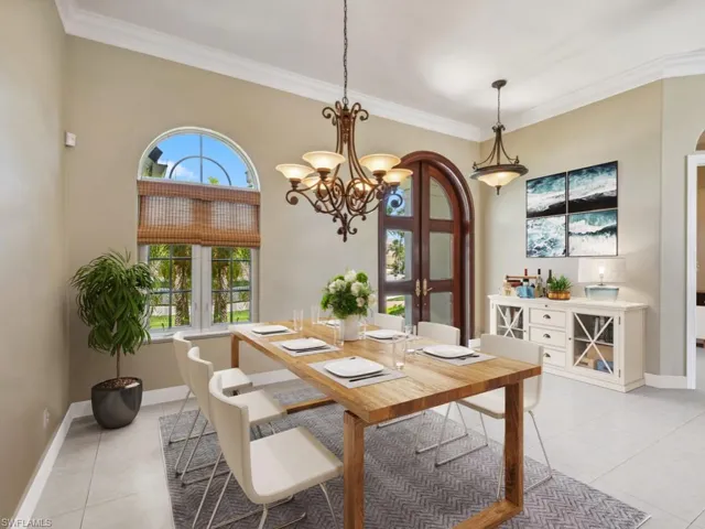 Dining space featuring light tile patterned floors, crown molding, baseboards, a chandelier, and healthy amount of natural light