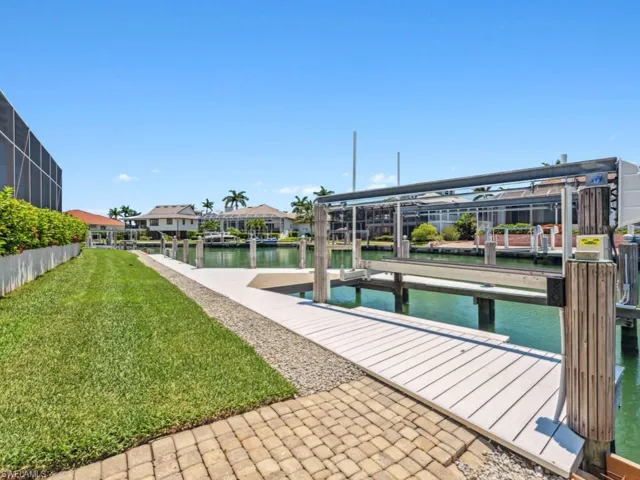 Dock area featuring a water view, boat lift, and a yard