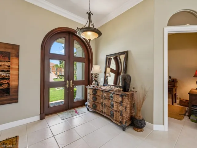 Foyer entrance featuring french doors, ornamental molding, light tile patterned flooring, and baseboards