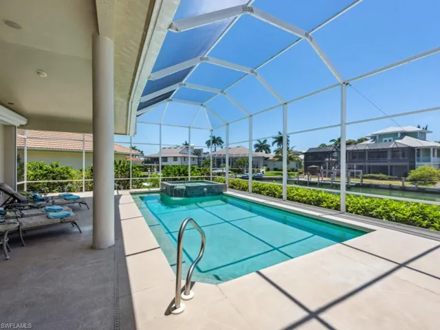 View of pool featuring a patio area, a residential view, a pool with connected hot tub, and glass enclosure